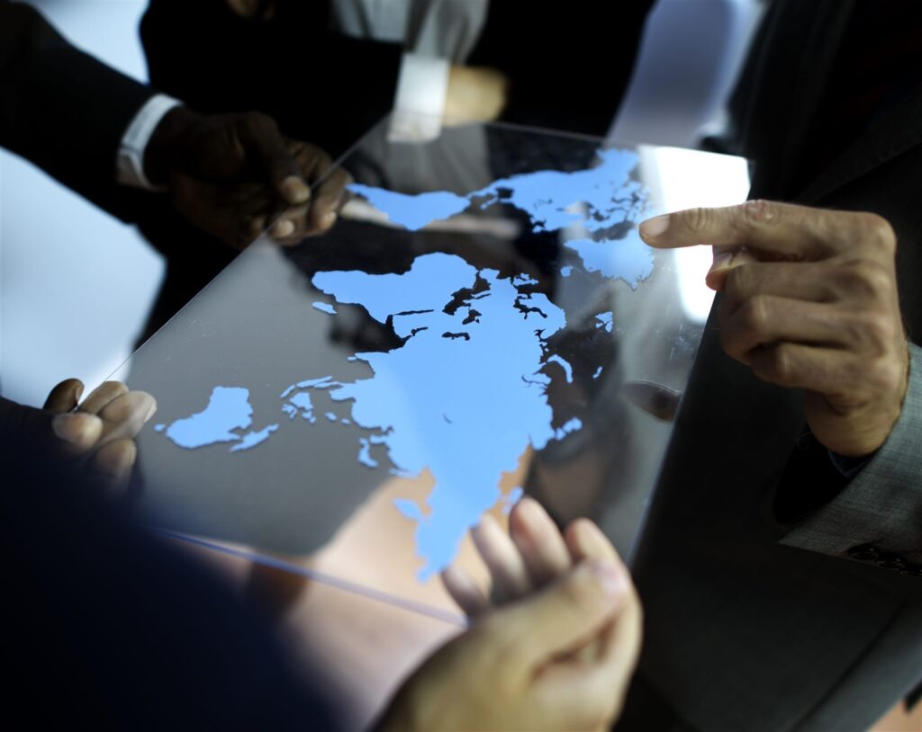 Business professionals pointing at a world map, representing global offshore audit teams